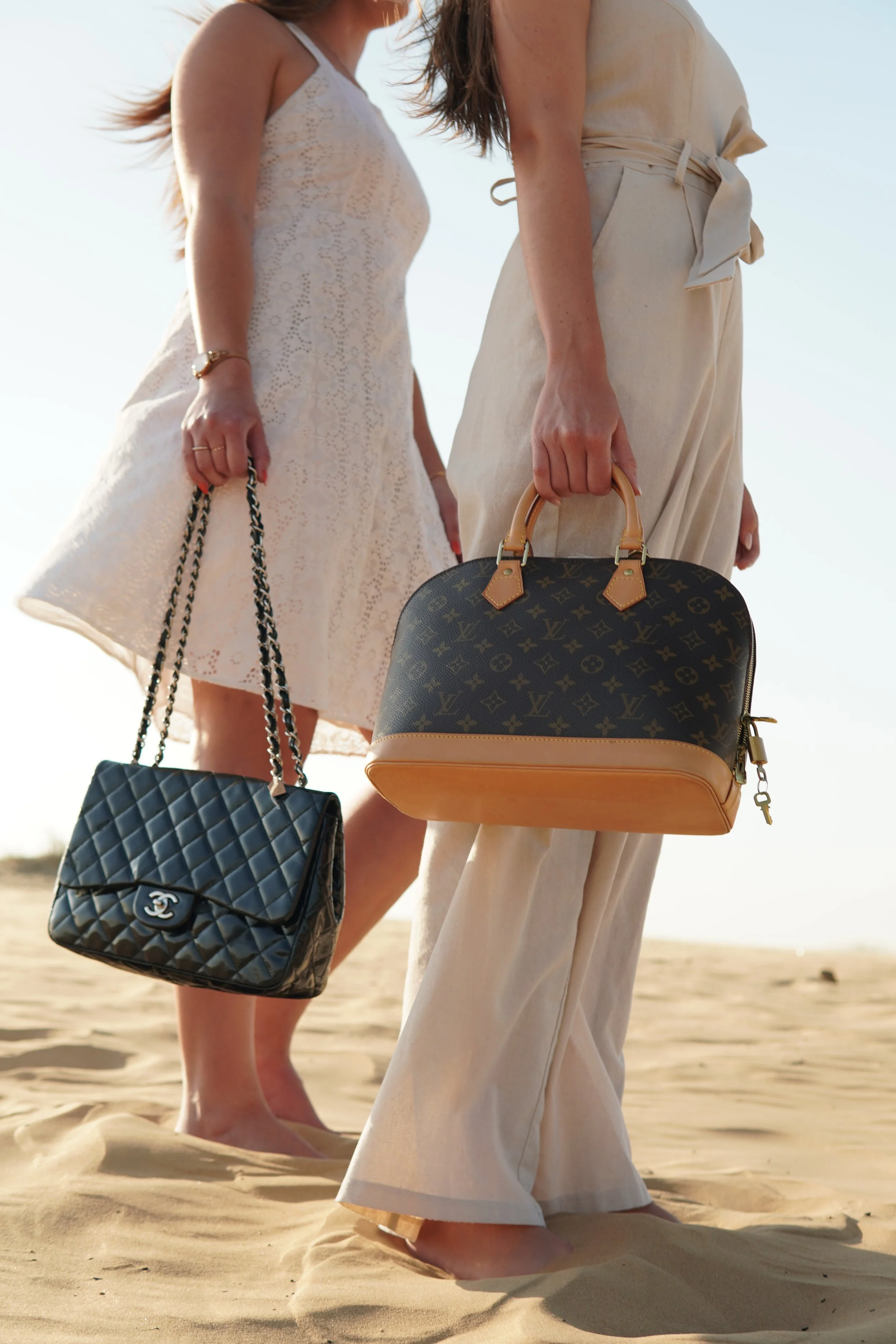 Two women carrying a Chanel quilted flap bag and a Louis Vuitton Alma